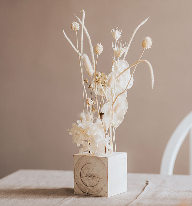 Weiße, elegante Trockenblumen in Holzwuerfel 